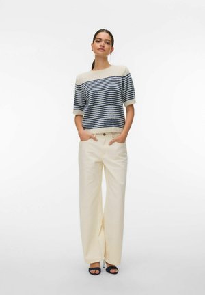 Pull rayé tricoté en marine et crème, manches courtes, col rond, associé à un pantalon large crème avec poches avant.