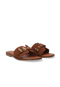 Brune ruskinds slide sandaler med to brede stropper, en gylden spænde og dekorative nitter på den øverste del, sat på en lysbrun flad sål.