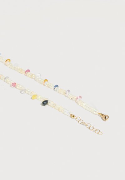 Deux chaînes délicates, semblables à des perles, avec de petites perles multicolores et des fermoirs dorés sur un fond clair.