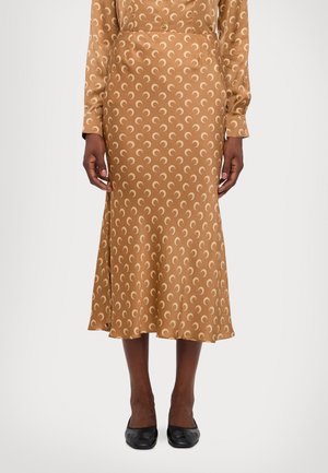 Jupe en satin marron avec des motifs en croissant crème, longueur midi, ourlet évasé, texture lisse, portée avec des chaussures plates noires.
