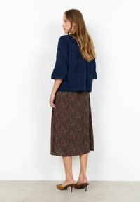 Námornícky ľahký sveter s 3/4 rukávmi, skombinovaný s dlhou hnedou sukňou s paisley vzorom. Outfit dopĺňajú hnedé podpätky.