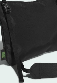 Borsa a tracolla nera con trama, realizzata con materiali riciclati. Dotata di chiusura con fibbia e tracolla regolabile. Piccola etichetta indica materiali ecologici.