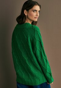 Maglione verde lavorato a maglia con un motivo a diamante testurizzato, polsini e colletto a costine. Il design presenta una vestibilità ampia e una texture morbida.