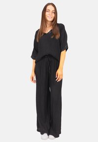 Ensemble noir en deux pièces en tissu léger. Comprend un haut ample à manches courtes et un pantalon à jambes larges avec une taille réglable par cordon.