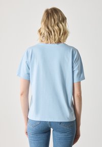 Lyseblå bomulls-T-skjorte med rund hals og korte ermer, med en avslappet passform og en glatt, ensfarget tekstur på baksiden.