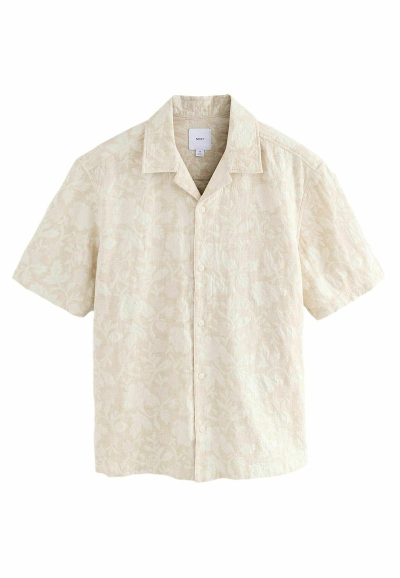 Camisa de manga corta en tejido beige claro con un sutil patrón floral, que presenta un cuello y cierre de botones en la parte delantera.