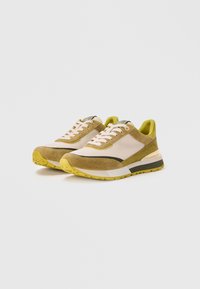 Sneakers met beige suède en mesh materiaal, limoen groene accenten, vetersluiting en een gematteerde rubberen zool met grippatronen.