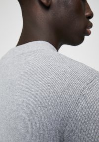 Gray ribbed sweater with a round neckline, featuring a textured knit pattern and a fitted silhouette, shown from the back.