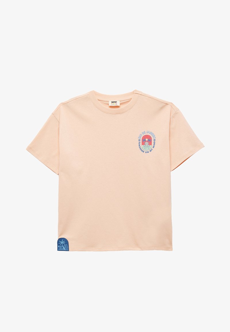 Peach cotton T-shirt with short sleeves. Features a circular graphic with "Rio de Janeiro" text and a blue accent near the hem.