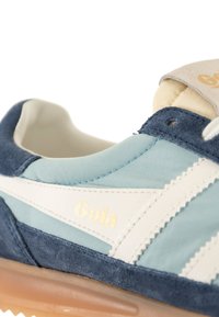 Sneaker blu e azzurro realizzato in suede e materiali sintetici, con accenti bianchi, dettagli cuciti e un logo dorato.