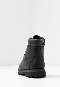 Botín de cuero negro con acabado texturizado, punta redonda, cuello acolchado y sistema de cordones. Suela de goma con patrón de tracción para mayor agarre.