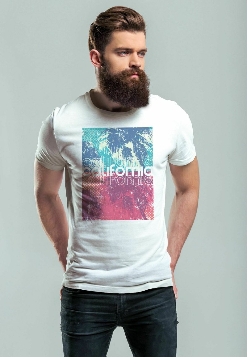 Weißes Baumwoll-T-Shirt mit einer bunten Grafik von Palmen und dem Wort "Kalifornien" in fettem, stilisiertem Text. Schwarze Jeans getragen.
