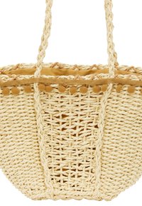 Vævet strandtaske i naturlig farve med tekstureret mønster, featuring en blød gul foring og dekorative pom-poms langs den øverste kant.