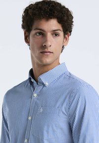 Blauw en wit gestreept overhemd met knoopsluiting, kraag en een zak op de linkerborst, gemaakt van lichtgewicht stof met een zachte textuur.