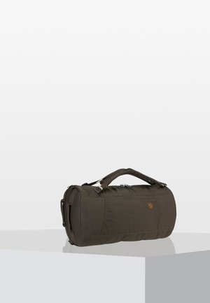 Sac de sport vert foncé en tissu durable, de forme ronde, avec des poignées supérieures et un logo discret sur un côté. Fermeture éclaire.