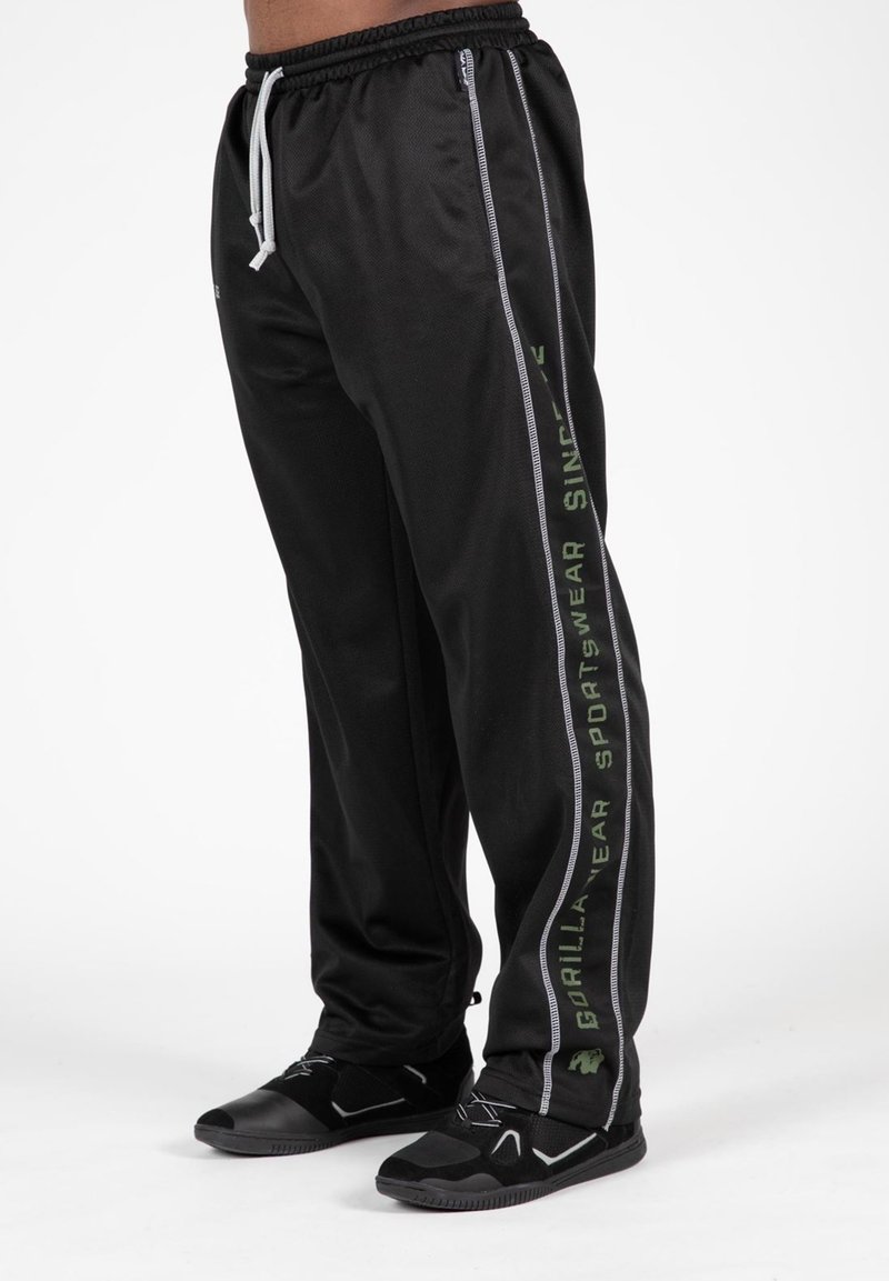 Zwarte sportbroek met een ontspannen pasvorm, voorzien van een trekkoord in de taille en zijstrepen in grijs en groen met branding. Geweven stof.