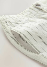 Lightweight, striped shorts in white with gray lines. Features an elastic waistband and side pockets with a soft, textured fabric.