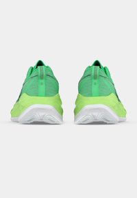 Zöld sportcipő texturált felsőrésszel, párnázott talppal és fehér középtalppal. Saroknál húzófüllel és enyhe fényvisszaverő részletekkel.