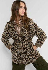 Cárdigan de estampado de leopardo en beige y negro, con cintura ceñida, mangas largas y tejido de punto texturizado. Acentos entrelazados en los puños.