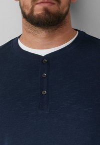 Himmelblaues Henley-Shirt aus strukturiertem Stoff, mit Rundhalsausschnitt, Drei-Knopf-Leiste und kontrastierendem Innenkragen.