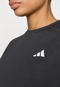 Czarna koszulka z okrągłym dekoltem i krótkimi rękawami. Posiada biały akcent w postaci logo po lewej stronie. Gładka tekstura materiału.