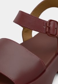 Σανδάλι από δέρμα βουργουνδίας με φαρδιά λωρίδα και ρυθμιζόμενο αγκράφα, με λεία υφή και σχέδιο με χοντρό τακούνι.