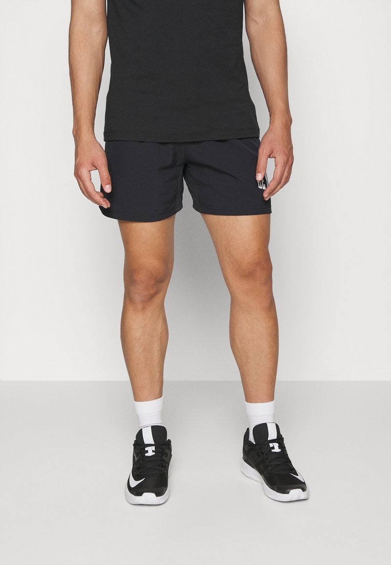Shorts de sport noirs avec une ceinture élastique, associés à des baskets noires avec des accents blancs, et des chaussettes blanches montantes.