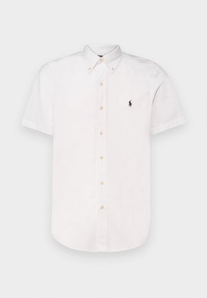 Camisa de botones blanca de manga corta, hecha de algodón, con cuello puntiagudo, botones beige y un pequeño logo bordado en negro en el pecho.