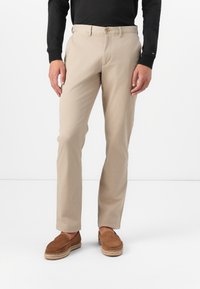 Beige katoenen chino's met een rechte snit, voorzakken, knoopsluiting en een soepele textuur. Gecombineerd met bruine instappers.