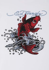 White t-shirt featuring a colorful, rhinestone-embellished design of a red fish on waves, with blue text "Ed Hardy" above.