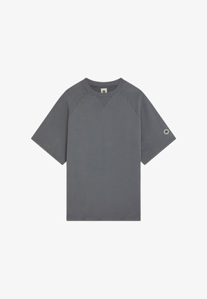 T-shirt gris foncé à manches courtes et col rond côtelé, avec des manches raglan et un petit œillet métallique sur la manche gauche.