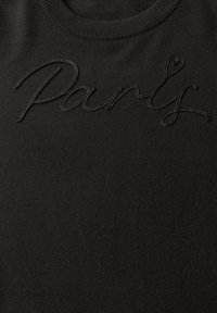 Pull en maille noire avec le mot "Paris" brodé en fil noir texturé sur la poitrine et un col rond.