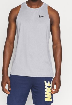 Szary bezrękawnik sportowy z czarnym logo Nike na klatce piersiowej, zestawiony z niebieskimi szortami z żółtym napisem "NIKE" po boku.