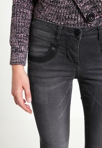 Zwarte denim skinny jeans met een gladde textuur, voorzien van twee zijzakken, een knoopsluiting en gedetailleerde stiksels langs de zijkanten.