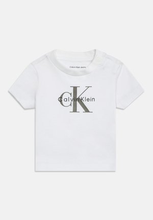 Valge puuvillane beebitees, lühikeste varrukatega, ümmarguse kaelusega, külje nuppudega ja ees suures hallis "Calvin Klein" logo trükiga.