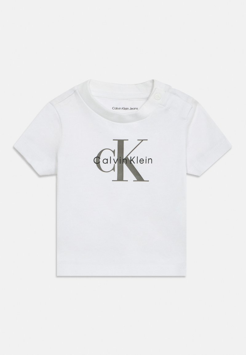 Biała bawełniana koszulka dla niemowląt z krótkimi rękawami, okrągłym dekoltem, zapięciem na napy z boku oraz dużym szarym logo "Calvin Klein" nadrukowanym z przodu.