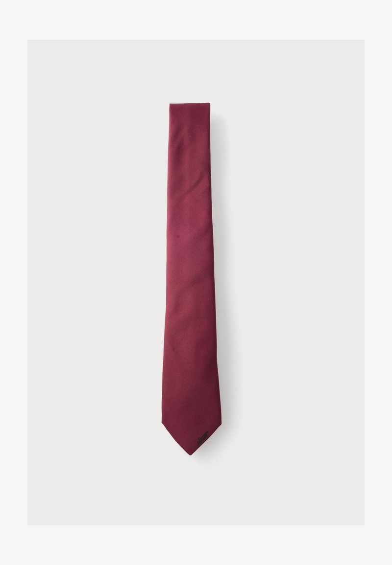Cravate homme rouge foncé uni avec une extrémité étroite et une texture subtile sur fond blanc.
