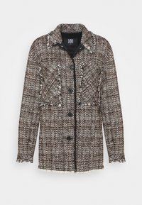 Veste en tweed marron et blanc à manches longues, quatre boutons noirs, deux poches poitrine et bords effilochés au col et aux poignets.