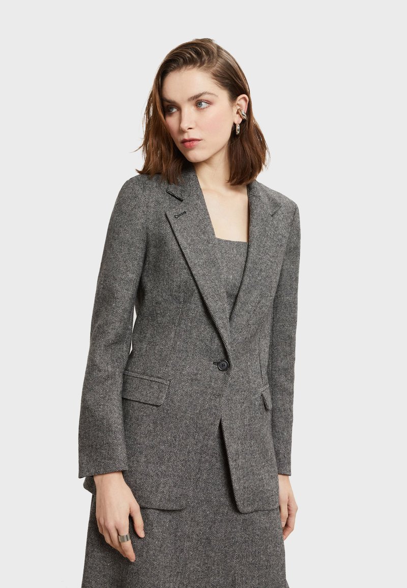 Sivý herringbone blazer s priliehavým strihom, s klopami, dvoma prednými vreckami a jedným gombíkovým zapínaním. Hladká textúra, všestranný dizajn.