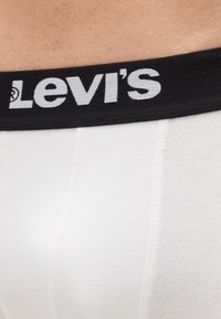 Biele bavlnené boxerky s čiernym elastickým pásom. Pás je výrazne zdobený bielym logom "Levi's".