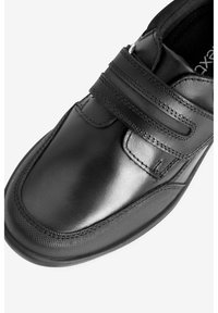 Schwarzer Lederschuh mit zwei Klettverschlüssen, abgerundeter Zehe, glatter Textur und dezenten Steppdetails an den Seiten.