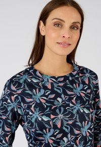 Blusa floreale in blu navy scuro con motivo floreale rosa e teal. Presenta un collo rotondo e un tessuto testurizzato. Design aderente.