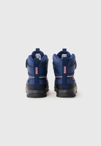 Een paar marineblauwe Puma winterboots met roze accenten, achteraanzicht met het merkembleem op de hieltreklussen en dikke zwarte zolen.