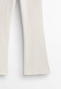 Beige flare broeken van een katoenmix, met zichtbare stiksels en een gestructureerd oppervlak. De benen zijn wijd aan de onderkant.
