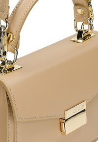 Beige leren handtas met gouden hardware, een klep sluiting en een geperst logo. Het heeft een gestructureerde vorm en een gladde afwerking.