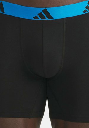 Zwarte boxershorts met een blauwe elastische tailleband met zwarte logo-accenten. De stof is glad en nauwsluitend met een lengte tot halverwege de dij.