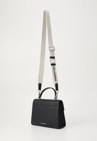 Borsa a tracolla in pelle nera con superficie a pietra, manico superiore, tracolla staccabile, dettagli in argento e tracolla bianca con la scritta "KARL LAGERFELD" in nero.