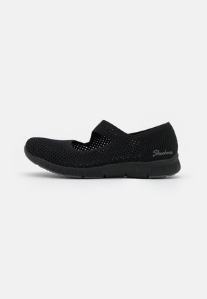 Czarny lekki but typu Mary Jane z siateczki, z regulowanym paskiem i elastyczną podeszwą, z logo Skechers na boku pięty.