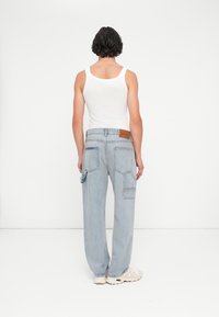 Denim hlače s cargo krojem v svetlo modri barvi, z ohlapnim in prijetnim fitom, z več žepi in rjavo usnjeno nalepko na pasu.
