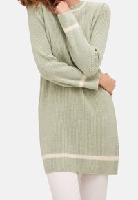 Maglione a maglia verde chiaro con maniche lunghe, caratterizzato da strisce orizzontali color crema ai polsini e all'orlo. Texture morbida, vestibilità rilassata.